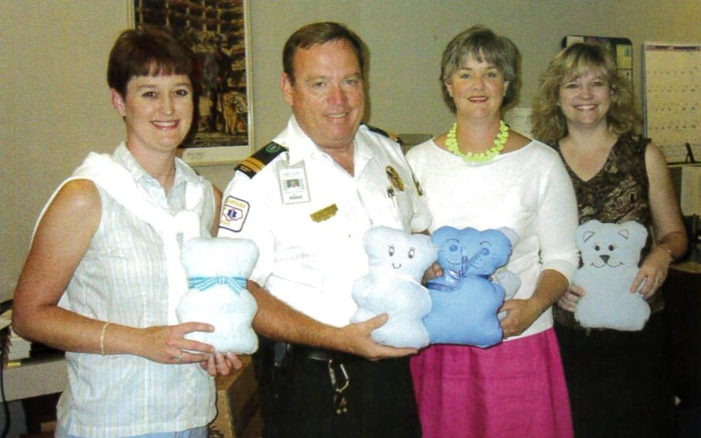 3 women and one man holding teddy bears